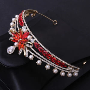 Detailed view of bridal crown with red zircon flowers and ivory pearls on gold alloy