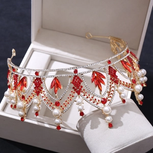 Détails d'une couronne de mariée dorée avec cristaux rouges et perles blanches