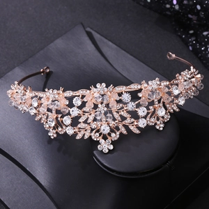 Detailed close-up of rose gold bridal headpiece with crystals and leaves on black stand