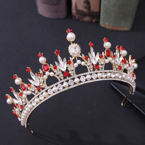 Détail macro de couronne baroque dorée avec strass rouges et perles blanches sur fond sombre