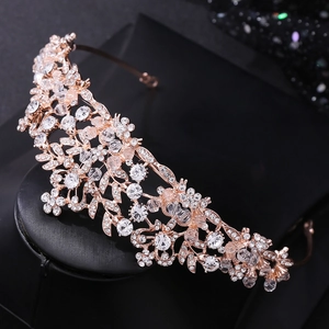 Close-up of rose gold bridal tiara featuring rhinestone leaves and crystal bead details