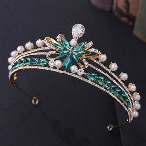 Vintage bridal crown with golden bow design, green zircons and pearls on black background