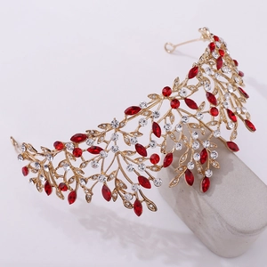 Close-up of golden leaf crown with red marquise rhinestones and white crystal details