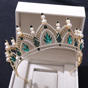 Gros plan du diadème de mariée doré avec pierres d'émeraude vertes et perles blanches