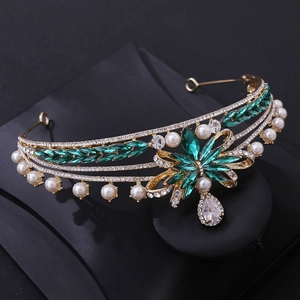 Detailed macro view of a vintage gold crown with emerald gems and teardrop pearls