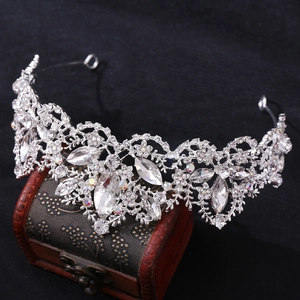 Detailed close-up of a silver crystal bridal crown on a vintage wooden box with black background