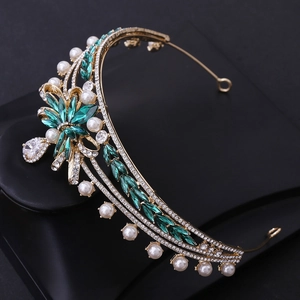 Close-up of emerald gemstones and white pearls on a gold-plated bridal crown