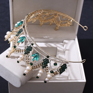 Détail de diadème de mariée doré avec strass verts et perles sur boîte blanche