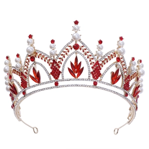 Détail d'une couronne dorée ornée de strass rouges étincelants et de perles blanches