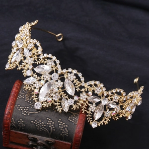 Elegant gold crown with sparkling crystals displayed on a vintage wooden jewelry chest