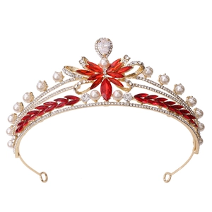 Detailed close-up of golden bridal tiara with red marquise rhinestones and white pearls