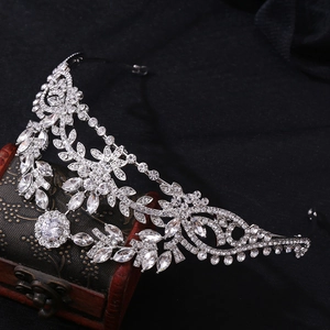 Detail shot of a silver bridal crown with leaf-shaped zircons on a dark vintage chest