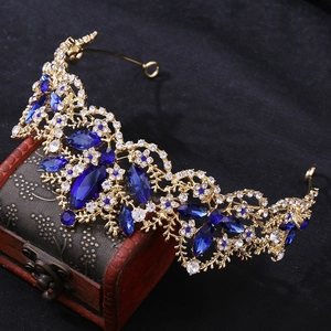 Detailed close-up of Baroque gold crown with blue marquise crystals on antique box