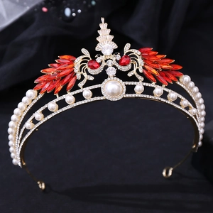 Close-up of golden bridal crown featuring red crystal peacock wings and white pearls