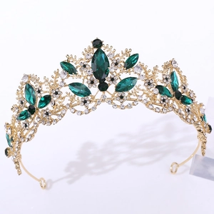 Close-up of golden crown featuring emerald green gems and sparkling clear rhinestones