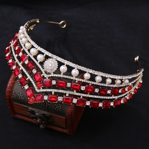 Détail d'une couronne de mariée dorée avec cristaux rouges et perles sur une boîte en bois