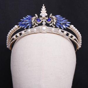 Luxurious gold bridal crown with blue gemstones and pearls on a sleek black background