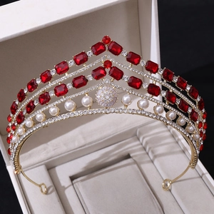 Vue détaillée de la couronne baroque dorée avec gemmes rouges et perles sur velours