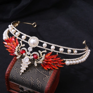 Detailed close-up of luxury bridal crown with red crystals and pearls on wooden box