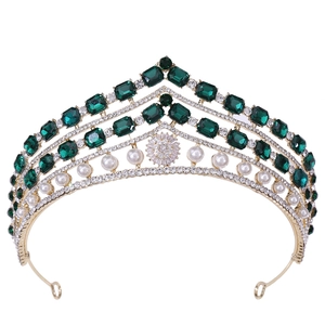 Détail d'une couronne dorée vintage avec pierres émeraudes et perles blanches