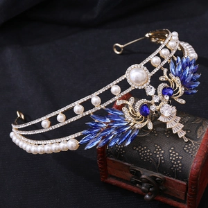 Detailed macro of crystal bridal tiara with blue marquise stones and white pearls on wood