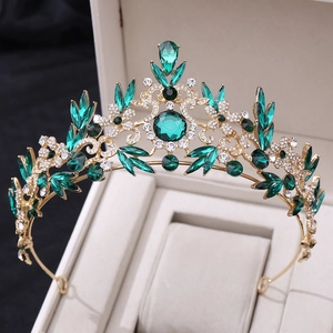 Détail d'une couronne baroque dorée avec cristaux vert émeraude et motifs de vignes