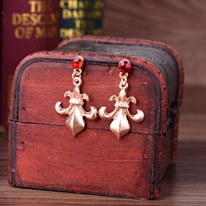 Macro detail of vintage gold fleur-de-lis earrings with red faceted ruby stones