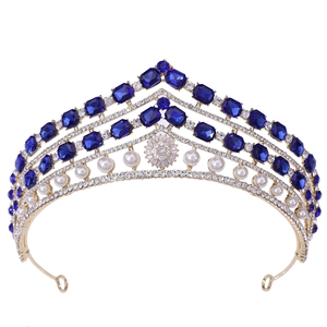 Couronne de mariée baroque dorée avec grands cristaux bleus et perles blanches sur fond blanc