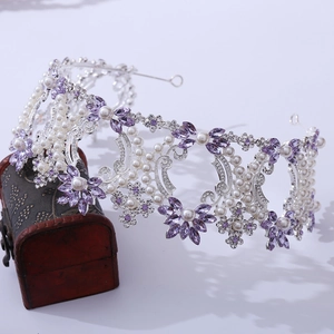 Detailed macro of baroque bridal crown with purple crystals and pearls on wood chest