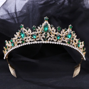 Detail of luxury bridal crown featuring emerald rhinestones and golden leaf patterns