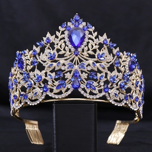 Detailed close-up of gold baroque crown with blue teardrop gems and sparkling crystals