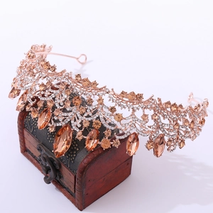 Luxurious rose gold bridal crown with champagne crystals on a vintage wooden treasure box