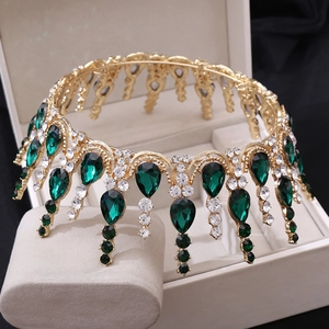 Gros plan d'une couronne de mariée dorée avec pierres vert émeraude et cristaux