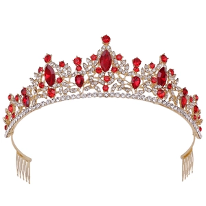 Detail view of a golden bridal crown with red pear-shaped rhinestones and hair combs