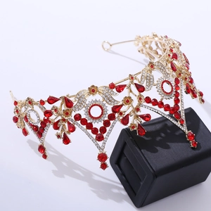 Macro detail of luxury gold bridal crown featuring red teardrop crystals and floral patterns