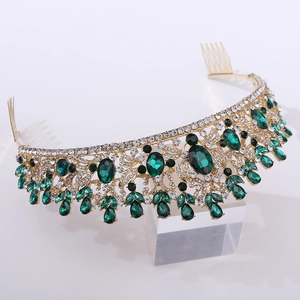 Detailed close-up of emerald green crystals and golden leaf design on the bridal hair comb