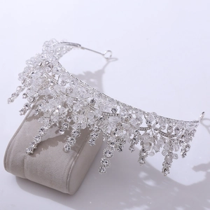 Detail of silver bridal tiara featuring drop crystals on a velvet display stand