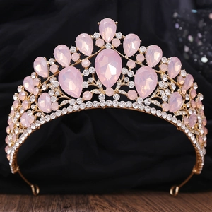 Detail of luxury gold tiara with pink teardrop crystals on black satin background