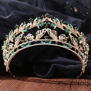 Dettaglio corona a farfalla vintage dorata con cristalli verdi su tulle nero di classe