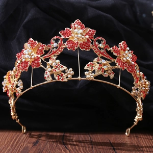 Detailed close-up of golden bridal crown with red and AB crystals on black velvet