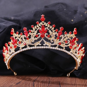 Gros plan d'un diadème de mariée doré avec strass rouges sur satin sombre