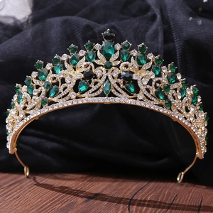 Detail of vintage gold crown featuring emerald green gemstones and sparkling rhinestones