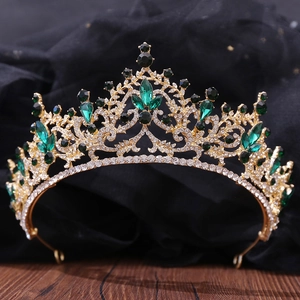 Gros plan d'une couronne dorée avec pierres vert émeraude et cristaux brillants