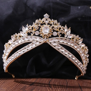 Close-up of golden bridal crown with sparkling rhinestones and leaf pattern on wood