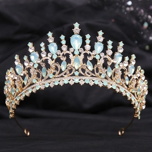 Gros plan de couronne baroque dorée avec cristaux bleu clair et strass sur tissu noir
