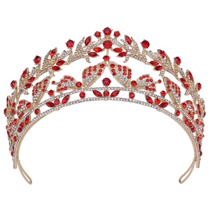 Dettaglio corona a farfalla dorata con strass rossi marquise e decorazioni a foglia