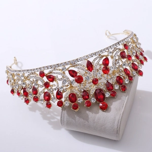 Detailed side view of a gold bridal crown with red gemstones and crystals on grey velvet