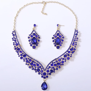 Detail view of gold bridal jewelry set with pear-cut deep blue crystals and teardrop pendant