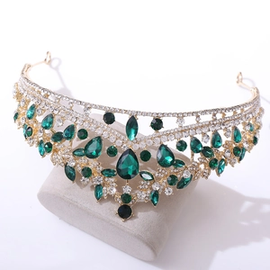 Detailed close-up of Baroque gold crown with emerald crystals and sparkling rhinestones