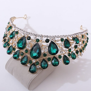 Detail of emerald waterdrop gems and white rhinestones on golden luxury bridal crown